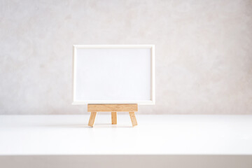 Empty picture frame mock up in minimalist interior on white table.