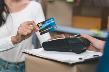 happiness businesswoman paying for her order with credit back card with delivery man from shipping company. Young women with new business about online shopping in home office and small store.