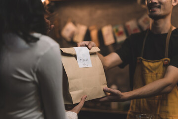 waitress and waiter service coffee cup and give bakery bag and bakery on plate to customer. the happiness man and woman in bakery small business on waiter and waitress uniform and service customer. © Atthapon