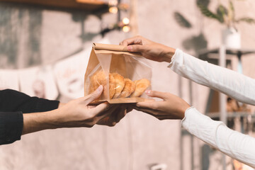 portraits of waitress service customer make a coffee on coffee machine holding bakery bag and give to customer. the happiness woman in bakery small business on waiter uniform and service customer.