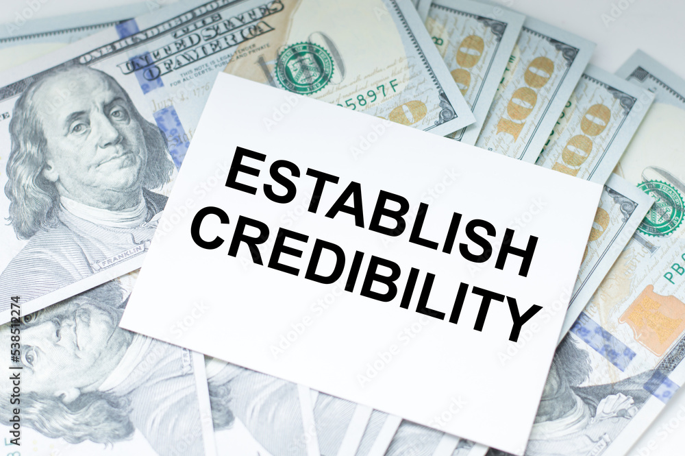 Poster establish credibility text on a card against the background of dollar bills on the table