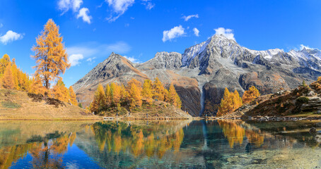 Panorama of Lac Bleu of Arolla lake in Canton Valais in colorful autumn season with reflection of Dent de Veisivi and Dent di Perroc peaks.