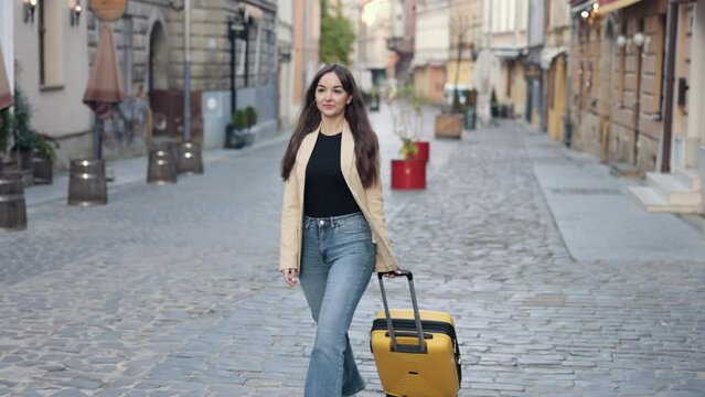 Female tourist, business traveler, vacation trip, pulling suitcase. Female tourist walking down the street with suitcase in a European city, tourism in Europe, pulling luggage, Travel Concept