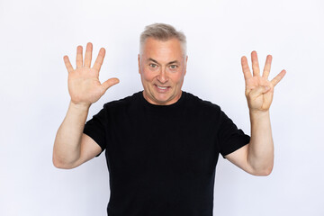 Naklejka premium Portrait of happy senior man showing nine fingers. Joyful Caucasian male model in black T-shirt with gray hair looking at camera, smiling while counting. Countdown concept.