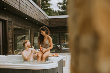 Young couple enjoying in outdoor hot tub on vacation