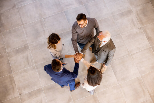 Business people team stack hands as unity gesture in the office hallway