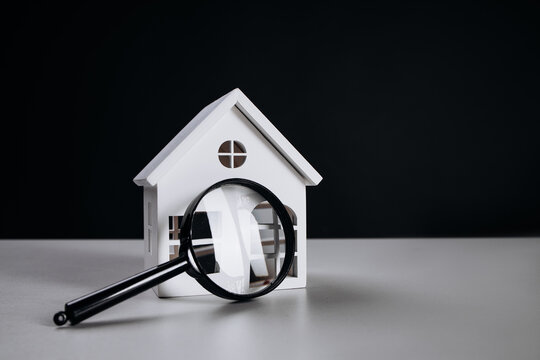 Magnifying glass and white house close-up. House selection and search, real estate concept.