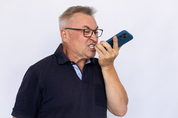 Senior man recording voice message. Male model in blue polo shirt expressing anger via voice message. Portrait, studio shot, voice message, anger concept