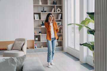 Smiling woman answering call, enjoying business conversation by phone in modern apartment at home