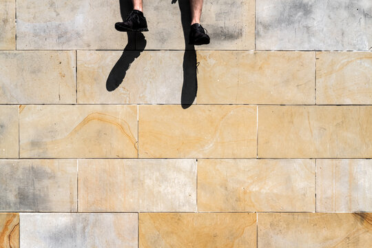 Feet Dangling Off Stone Wall In Bright Sunshine