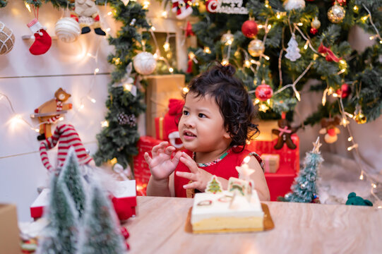 Happy Asian little girl with Christmas cake at home on winter holiday with family.