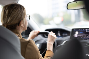 Business woman driving a car to work. Female driver steering car on the road