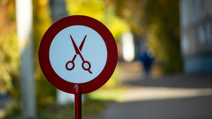 Red round sign with the image of scissors near the barbershop