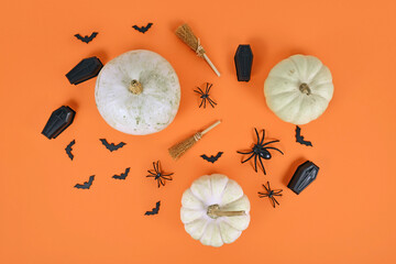 Halloween arrangement with white pumpkins, black spiders, bats and coffins and witch brooms on...