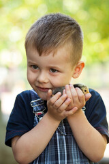 Little boy holding a baby chick on a farm. Portrait of little boy with chick outdoors at the day time.