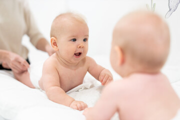 Beautiful shot of a cute baby boy looking at his reflection in big mirror.