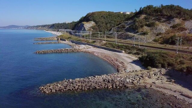 above the beaches with stone breakwaters near the railway station in the resort village near the Black Sea - aerial view on a sunny summer day
