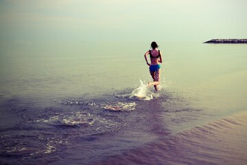 young girl runs on sea water during training with antique effect tones