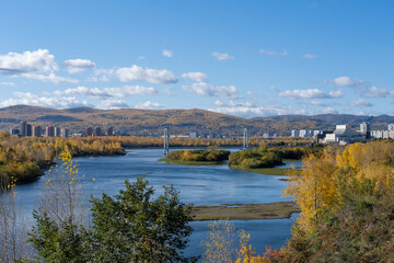 Obraz premium Autumn city landscape, view from the mountain to the river, and the bridge. Yellowing beautiful forest in the city park.