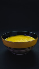 yellow and black ceramic bowl filled with pumpkin puree on a black background. Foodie. portrait picture