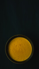 yellow and black ceramic bowl filled with pumpkin puree on a black background. Foodie. portrait picture