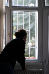 sad person watching outside from window