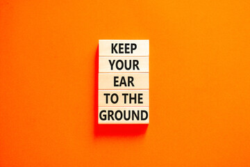 Keep your ear to the ground symbol. Concept words Keep your ear on the ground on wooden blocks. Beautiful orange table orange background. Business keep your ear on the ground concept. Copy space.