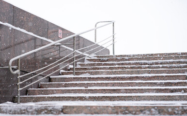 Granite steps in winter in the snow. The danger of slippery steps in the cold. Snow removal in...
