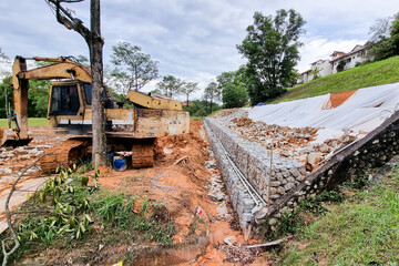 Series of slope retention construction design with rocks and mesh to manage landslide