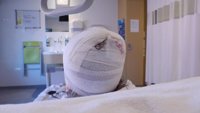 Head wound victim in hospital. Close up of head wrapped in bandages.