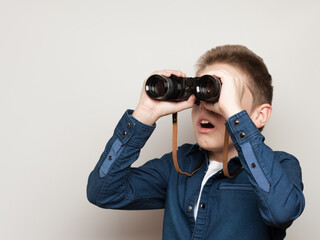 Fototapeta premium The boy makes observations looking through binoculars