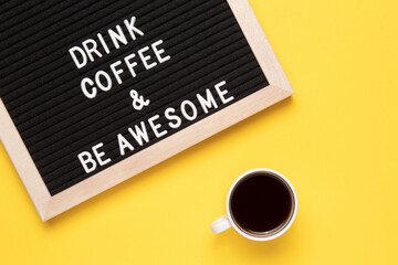 Top view of cup of black coffee and phrase drink coffee and be awesome on letter board.