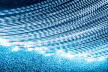 Bundle of optical fibers with lights in the ends. Blue background.