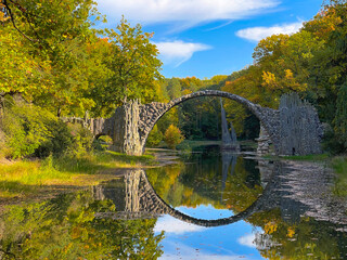 Fototapeta na wymiar Arch Bridge in Kromlau, Saxony, Germany. Colorful autumn in Germany. Rakotz bridge in Kromlau