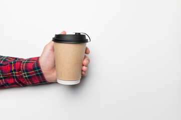 male hand in a plaid shirt hold a paper glass with a hot drink, with a place for an inscription, on a white background. studio shot