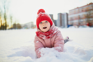 Fototapeta na wymiar Adorable preschooler girl having fun in beautiful winter park on a snowy cold winter day