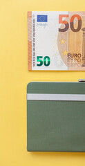 Fifty euro banknotes next to a notebook on a yellow background, Expense and budget planning. Cash paper currency, payment, earnings and savings, the concept of money and finance