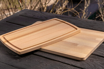 Pair of rectangular wooden cutting boards. Upper board with Juice Groove, made of beech. Lower one is glued from birch parts. Texture of birch and beech wood. On black background