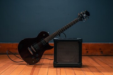 Electric guitar and an amp speaker on a wooden floor and gray background