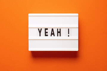 Lightbox with word yeah on orange background, top view. Space for text