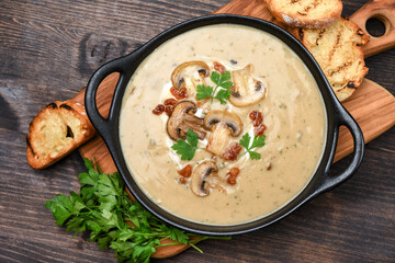 Mushroom soup with bread and fresh mushrooms on a wooden background