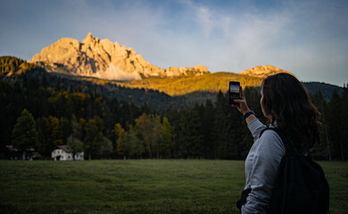girl is taking a picture  of the mountains, sunset time in Dolomites