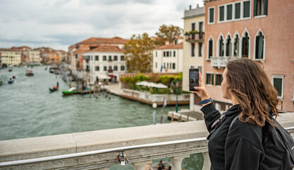 Fototapeta na wymiar Tourist girl is taking a picture from Wikipedia Ponte delle Guglie in Venice