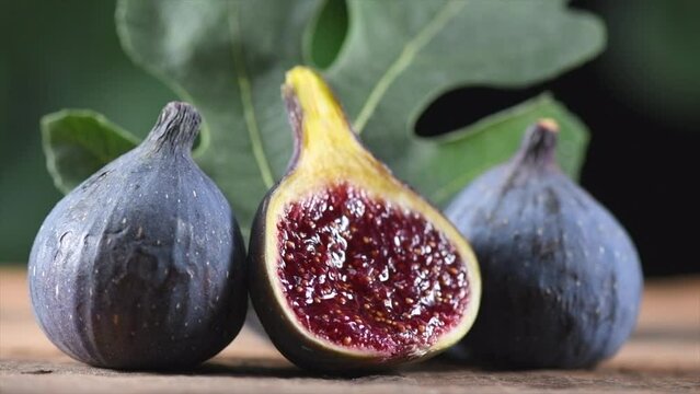 Ripe fig fruits with leaf close-up. Beautiful sweet fresh organic figs on a wooden table. Label design. Healthy vegan food. Slow motion