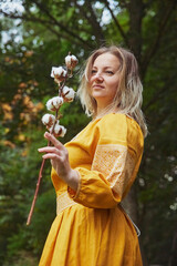 beautiful Ukrainian woman in embroidered dress holds a sprig of cotton