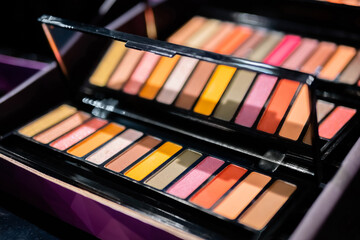 Colorful eyeshadow pallet for make up in cosmetic store - close up view. Makeup, beauty, fashion and glamour concept