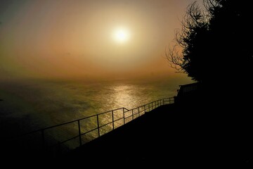 The sun sets in the sea on a hazy sunset from the Fio viewpoint west of Mdeira
