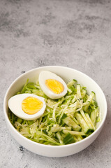 summer salad of Chinese cabbage with cucumber and egg in a white bowl on the table