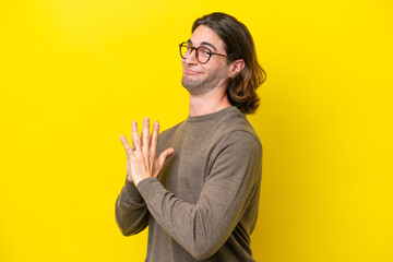 Caucasian handsome man isolated on yellow background scheming something