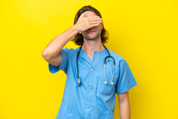 Young surgeon caucasian man isolated on yellow background covering eyes by hands. Do not want to see something